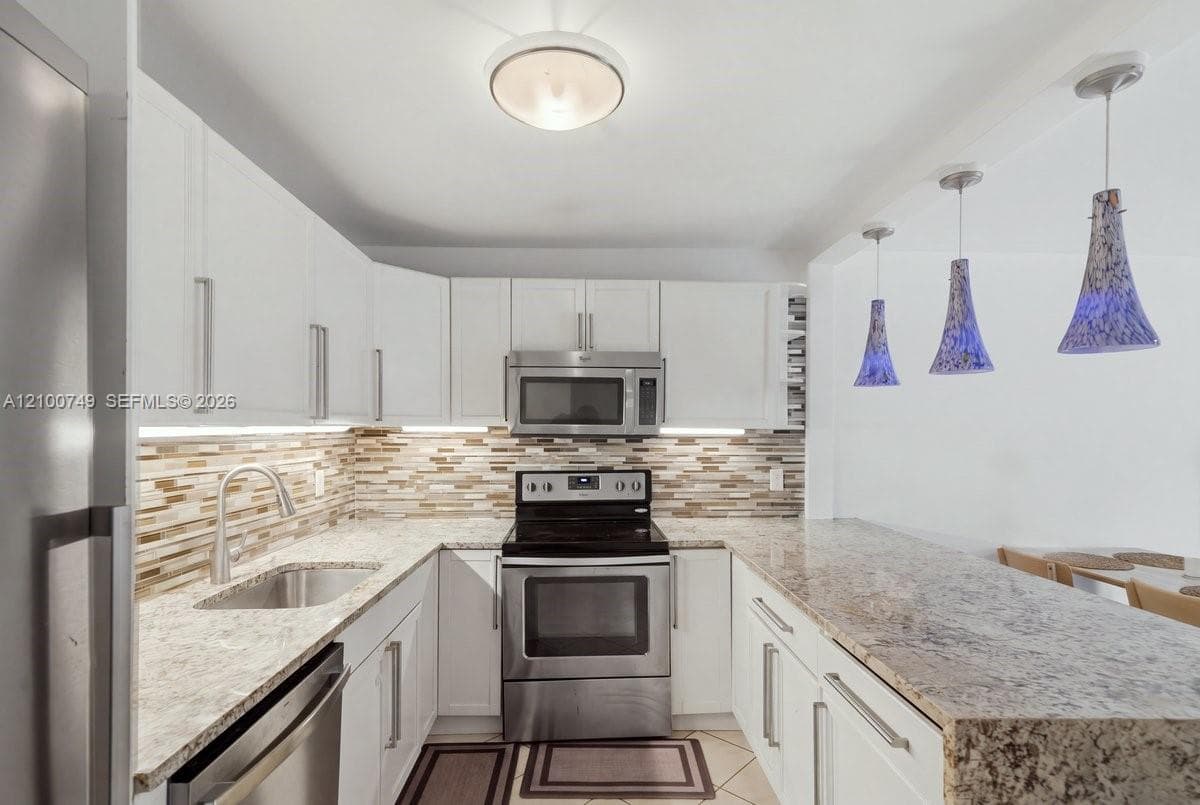 Interior hallway featuring neutral painted walls, diamond-patterned tile flooring, recessed ceiling lighting, and solid core doors with metallic hardware