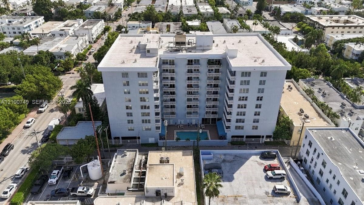 Aerial perspective of a multi-story mid-rise building featuring a flat roof and surrounding urban density, positioned within proximity to the coastline