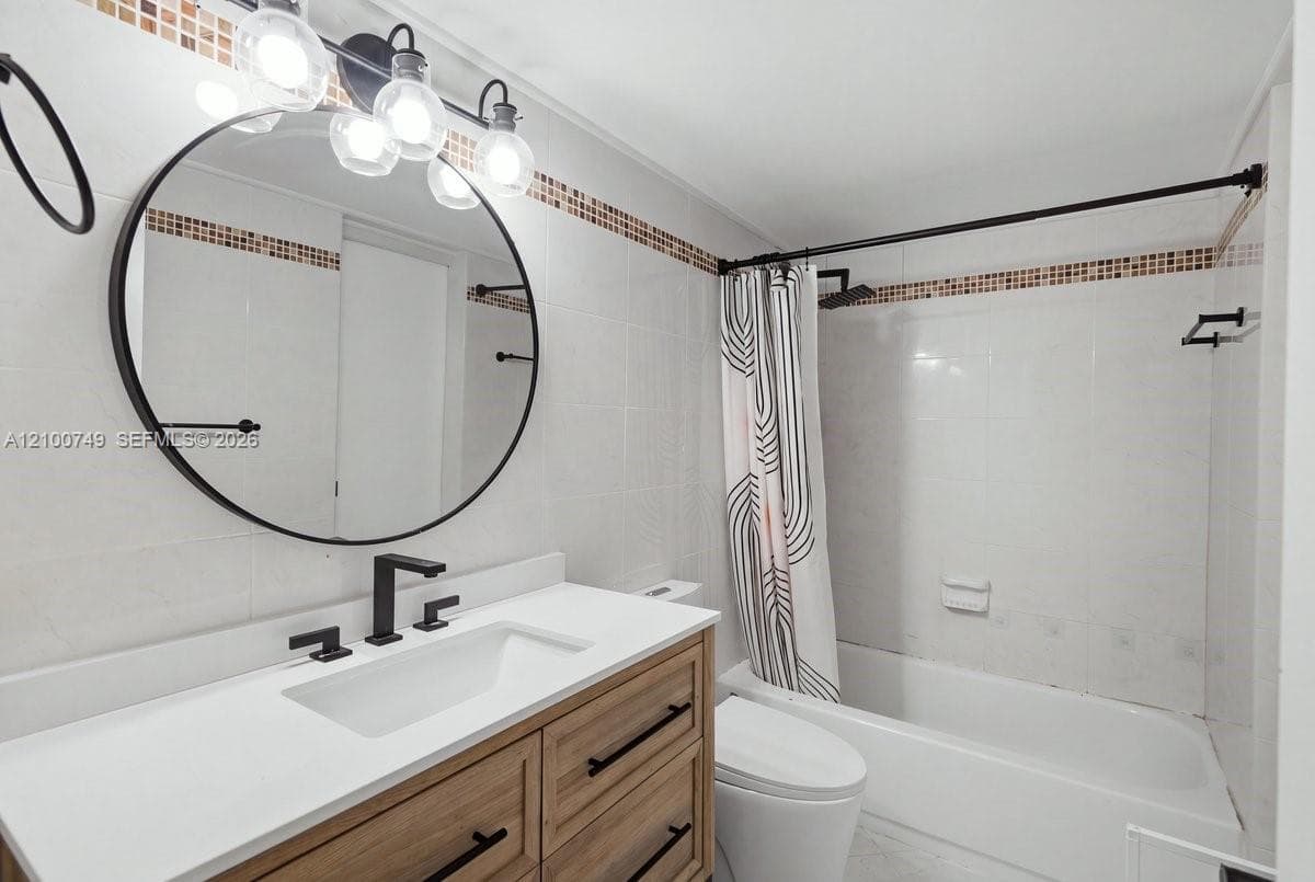 Neutral-toned room featuring wood-finish flooring and a ceiling-mounted light fixture with a three-blade fan