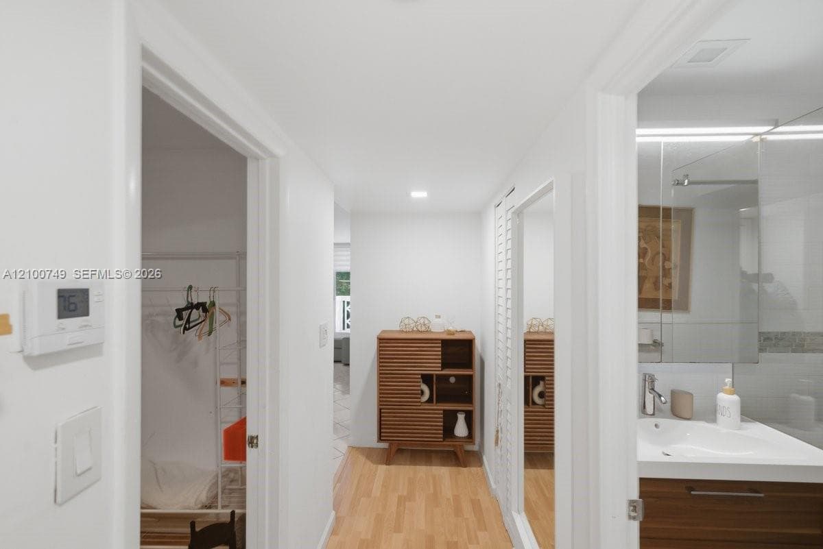 Hallway featuring wood-finish flooring, recessed lighting, and a built-in wall mirror with louvered trim