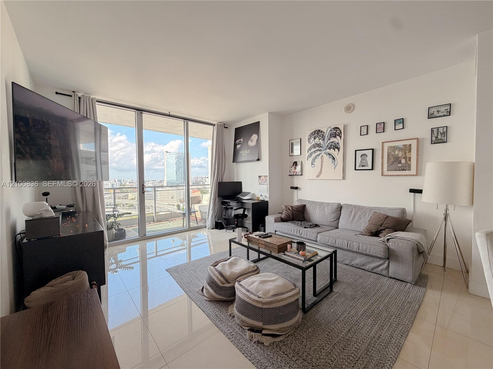 Living space featuring high-gloss tile flooring, floor-to-ceiling glass sliding doors, and a private balcony