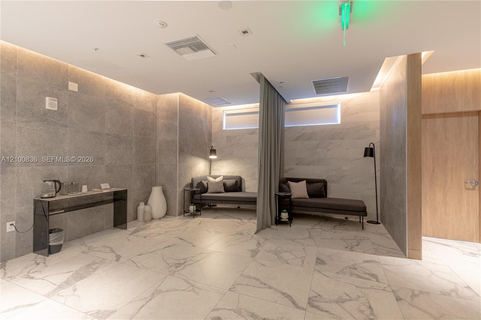 Large-format stone-tile flooring and wall cladding, recessed accent lighting, and wood-finish partition paneling