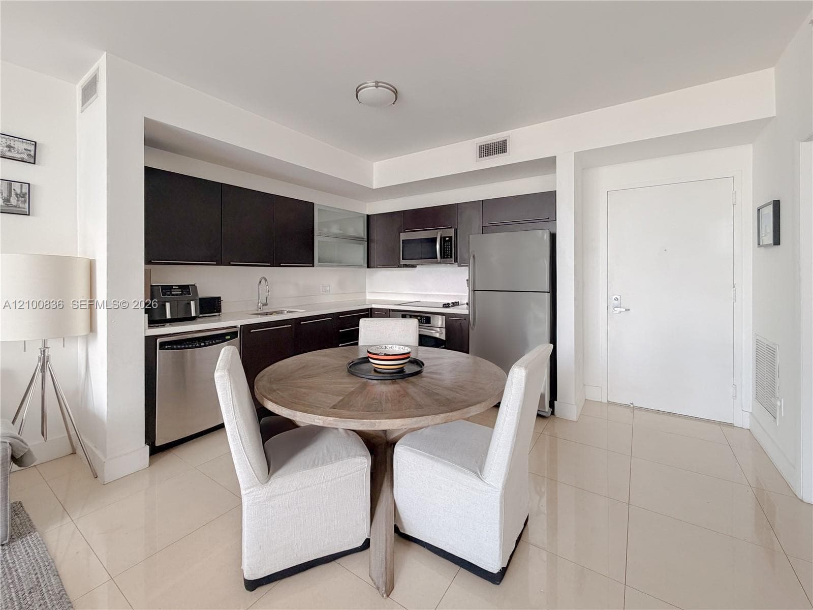Kitchen featuring dark cabinetry, stainless steel appliances, solid-surface countertops, and large-format tile flooring