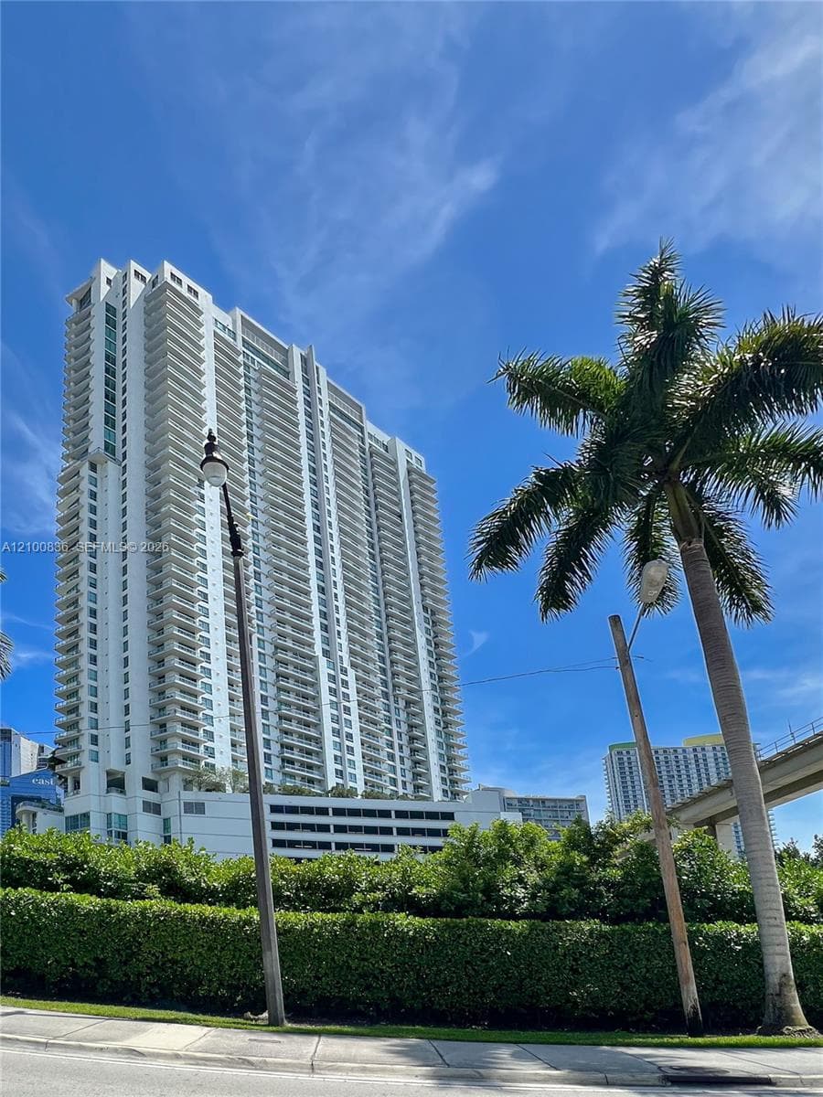 High-rise residential tower featuring white structural facade and private exterior balconies