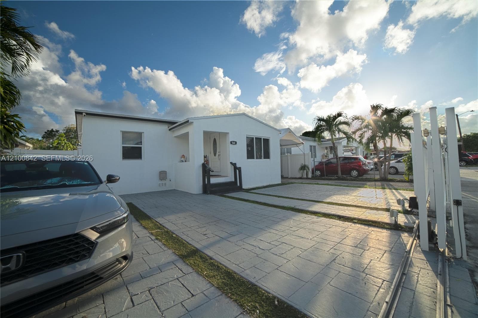 Stucco exterior featuring a paved driveway, front entryway porch, and metal perimeter fencing