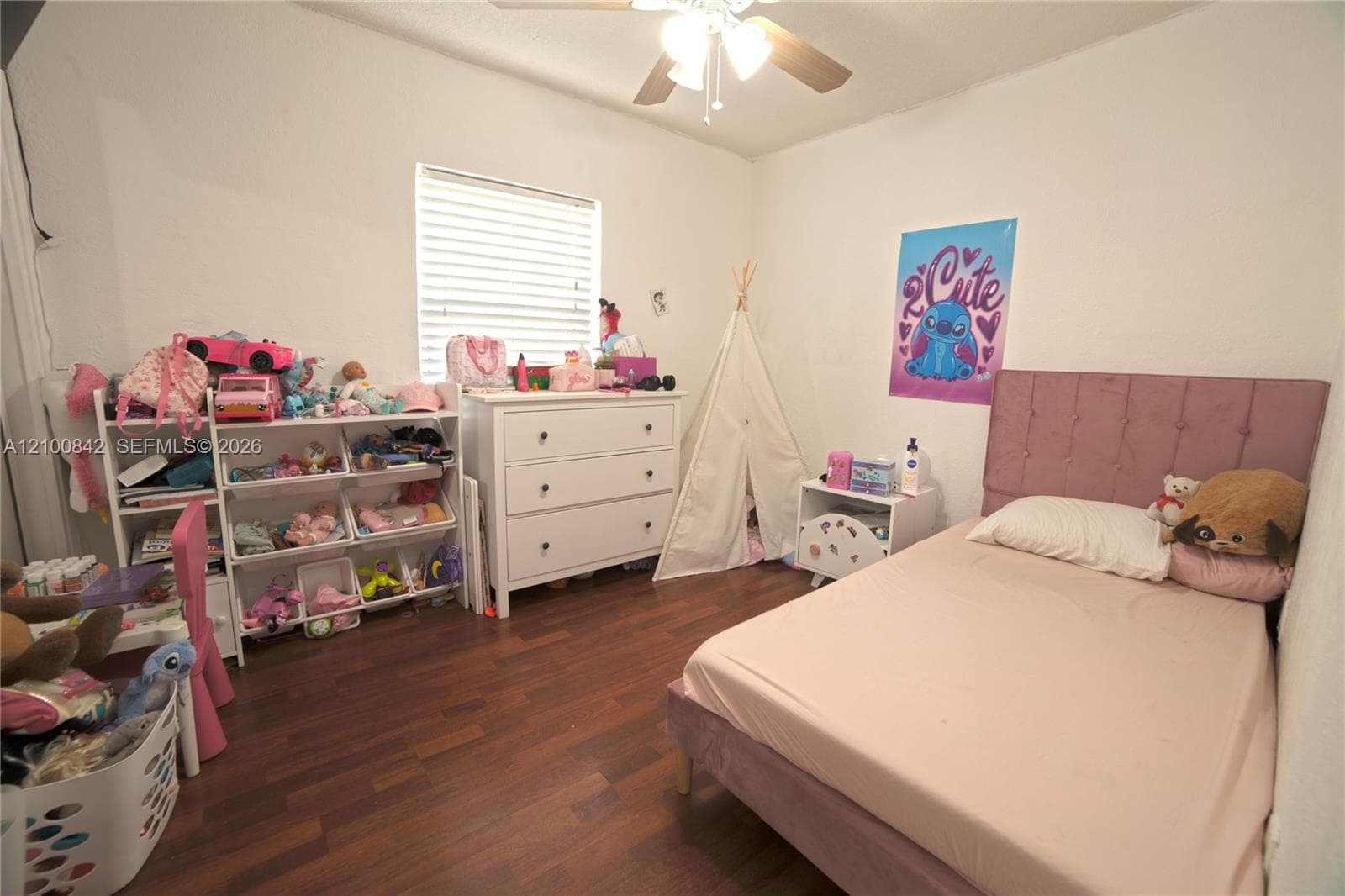 Bedroom featuring wood-finish flooring, a ceiling fan with integrated lighting, and a single window with horizontal blinds