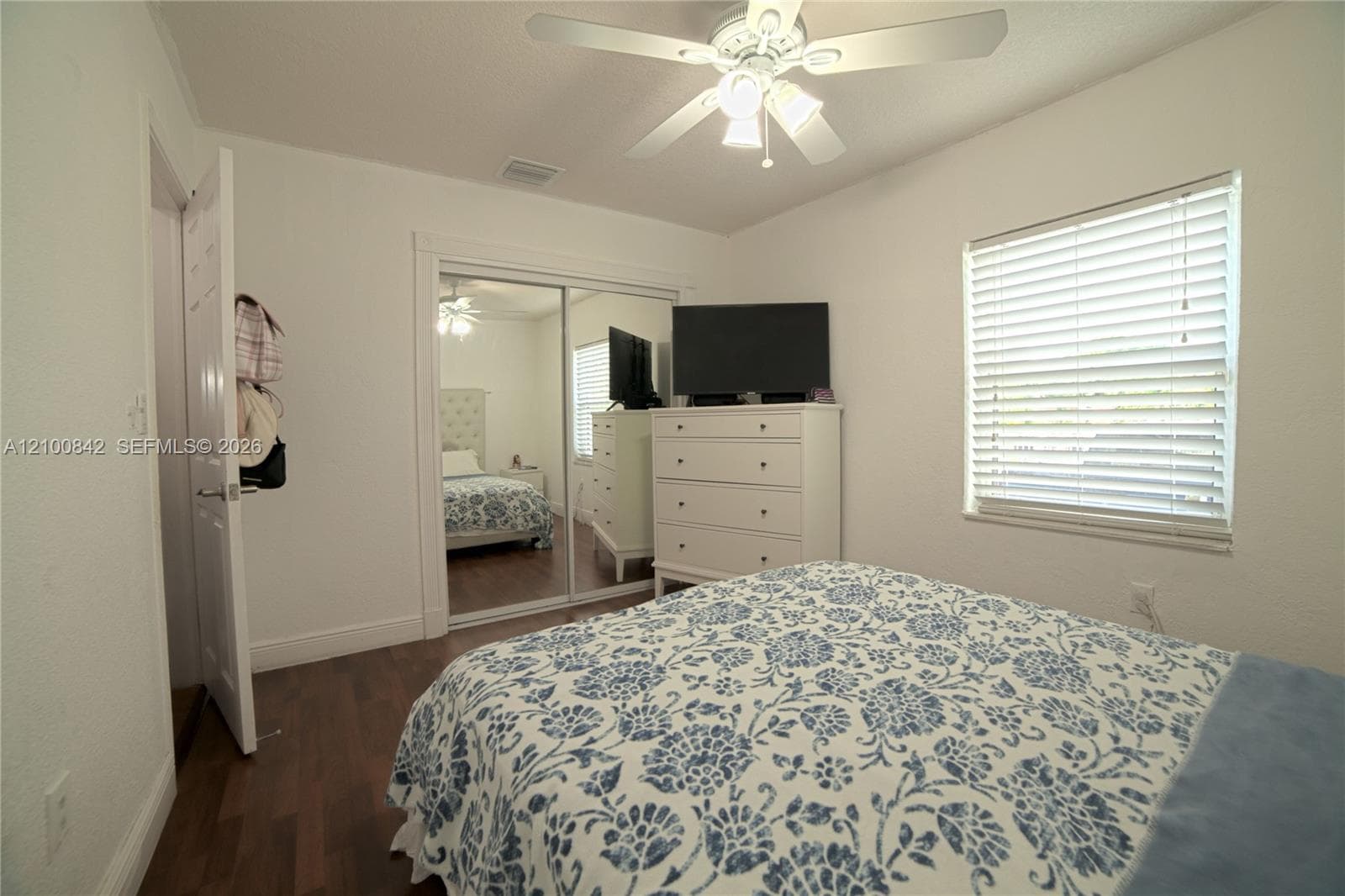 Wood-finish flooring, ceiling fan with integrated light fixture, and mirrored sliding closet doors