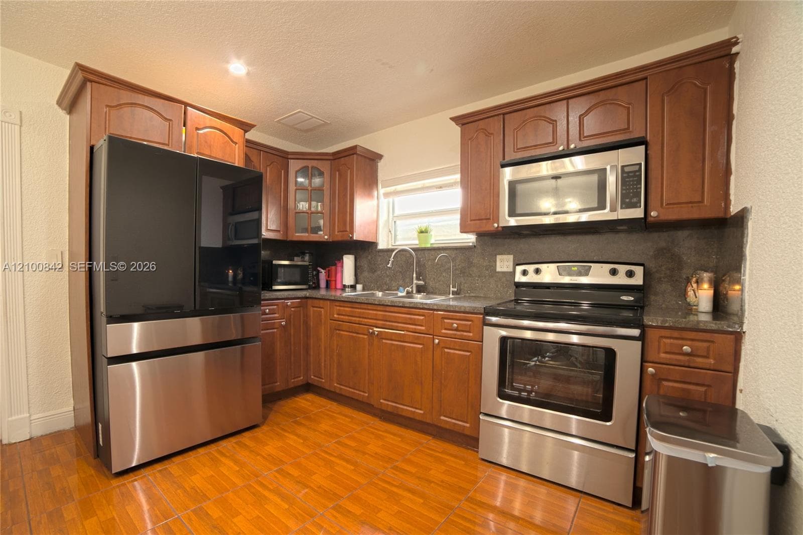 Kitchen featuring raised-panel wood cabinetry, stone countertops, stainless steel appliances, and wood-finish flooring