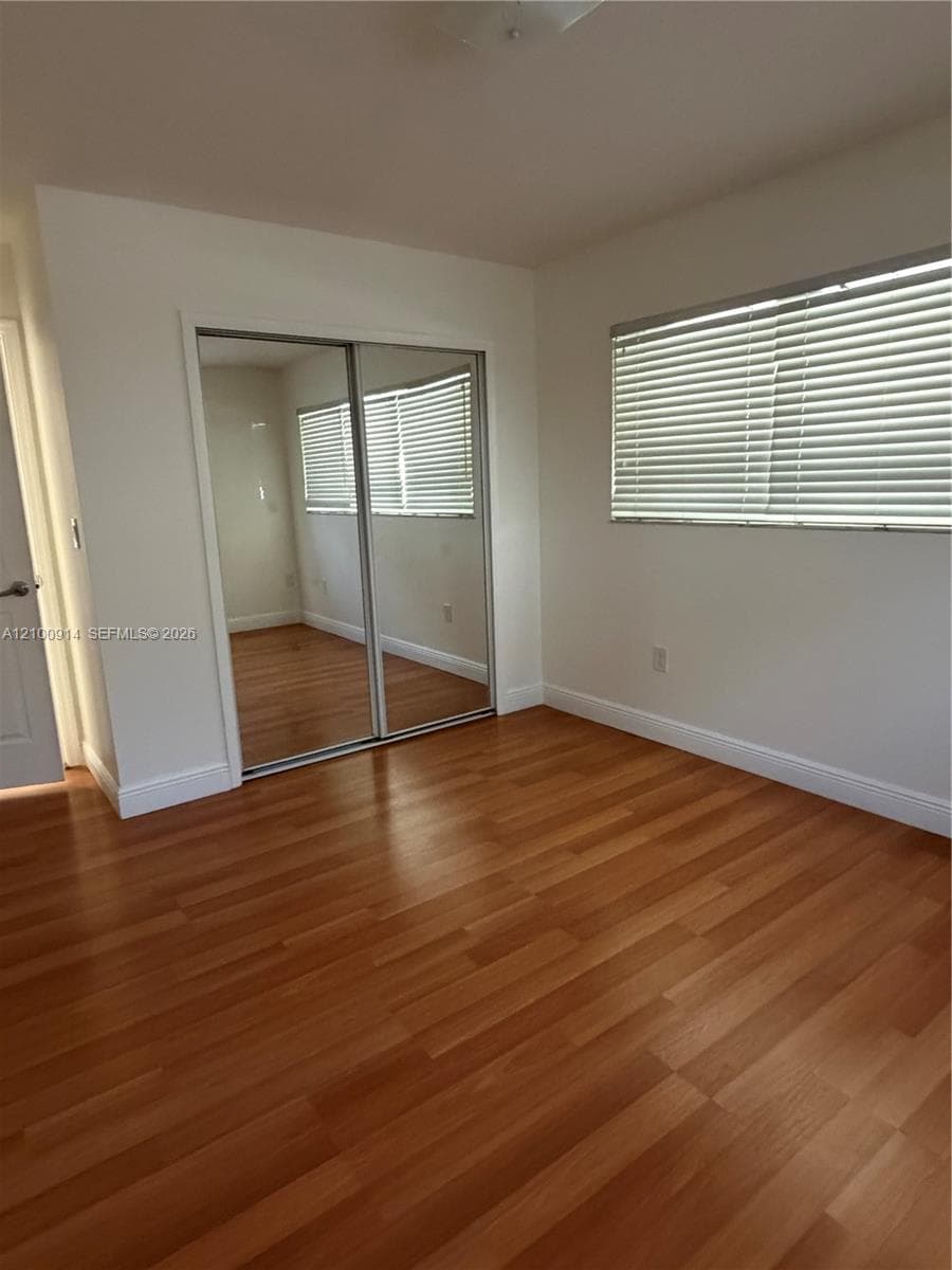 Wood-finish flooring, sliding mirrored closet doors, and window blinds