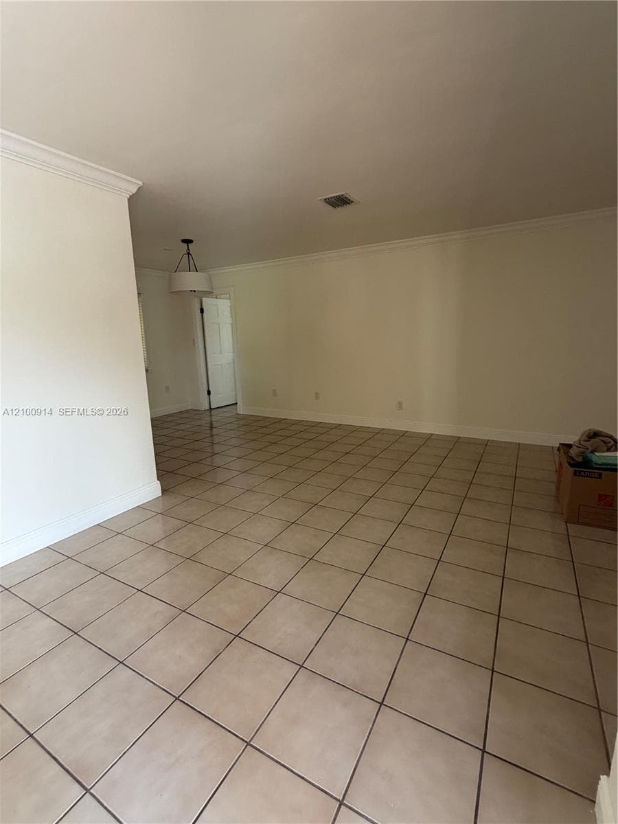 Interior space featuring ceramic tile flooring, crown molding, and a drum-style pendant light fixture
