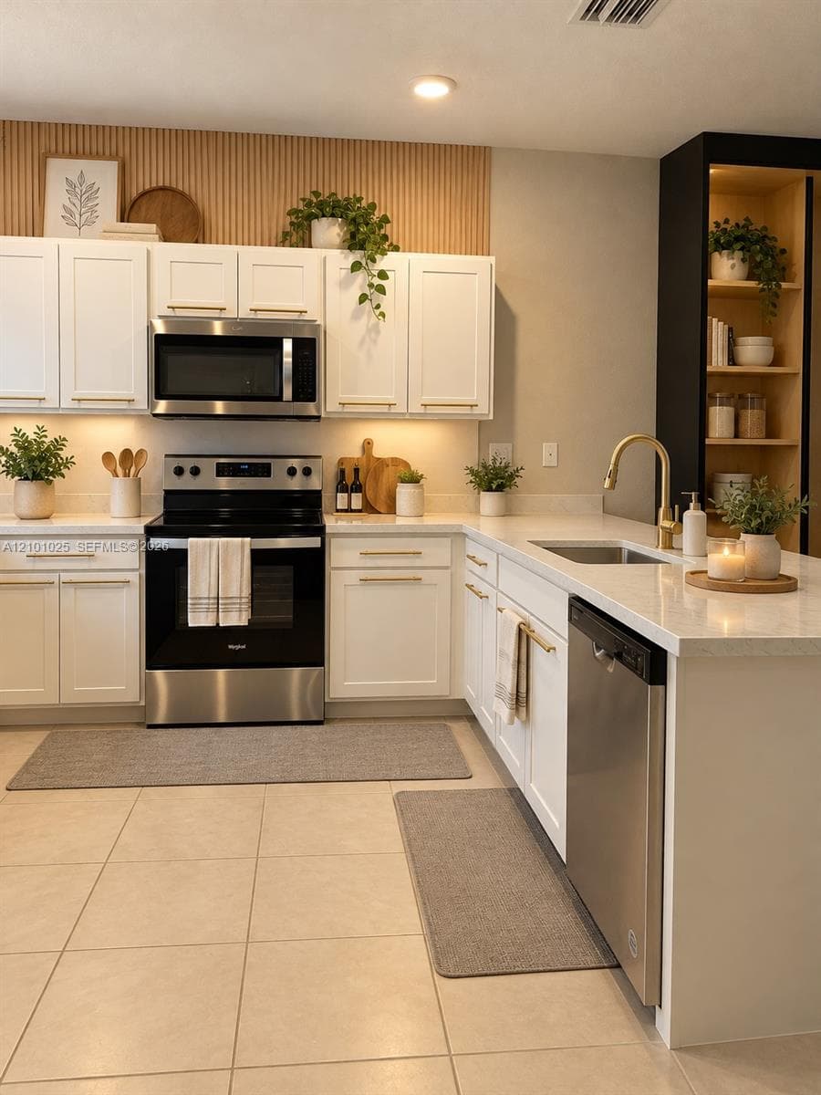 Kitchen featuring white Shaker-style cabinetry, stainless steel appliances, light-toned stone-finish countertops, brass-finish hardware, and a vertical wood-slat accent wall