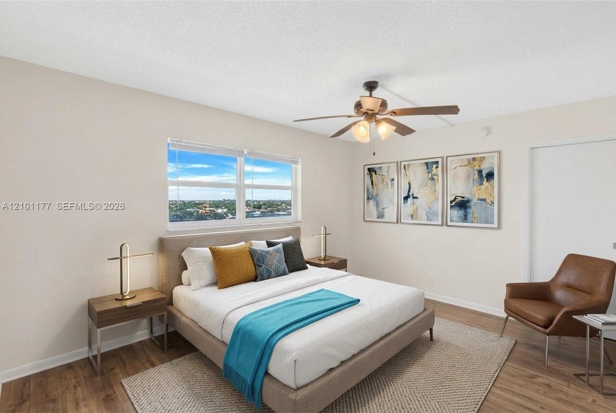 Neutral-toned interior featuring wood-finish flooring, a ceiling fan with integrated lighting, and a large window showcasing a panoramic outdoor horizon