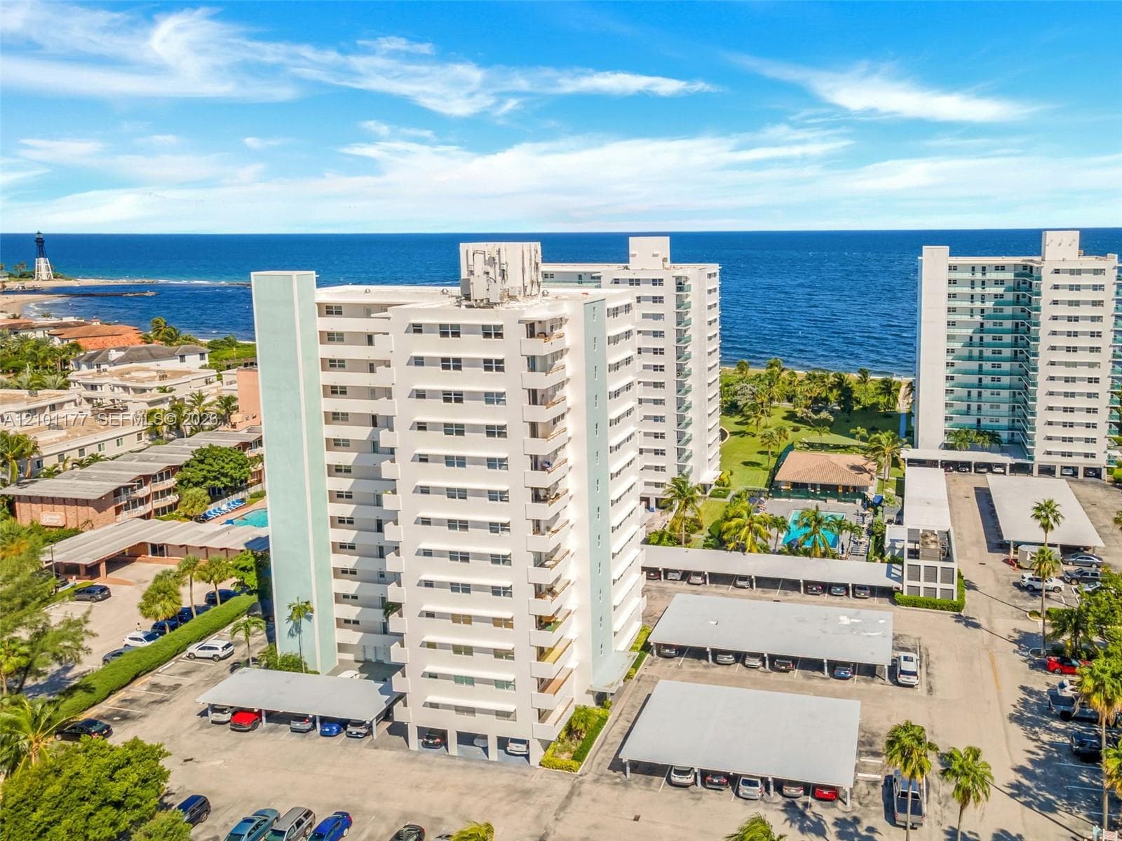 High-rise residential complex featuring covered parking, outdoor swimming pool, and oceanfront placement