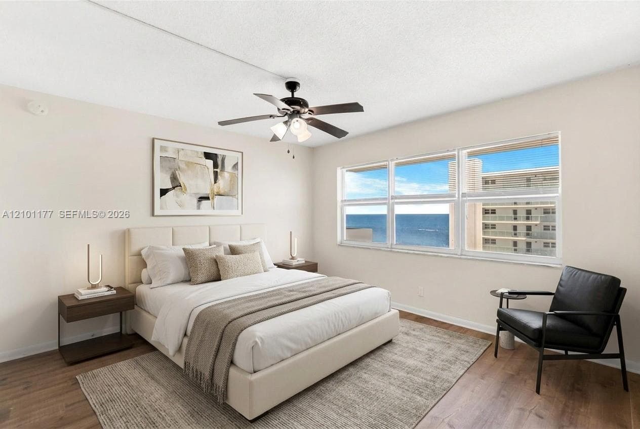 Bedroom featuring wood-finish flooring, a multi-blade ceiling fan with integrated lighting, and expansive horizontal windows
