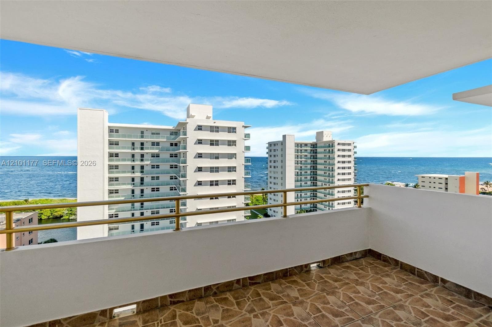 Covered balcony featuring stone-patterned tile flooring and metal railings