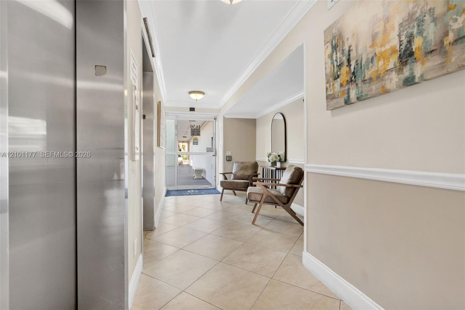 Elevator foyer featuring neutral tile flooring, crown molding, chair rail trim, and a glass-paneled entry door