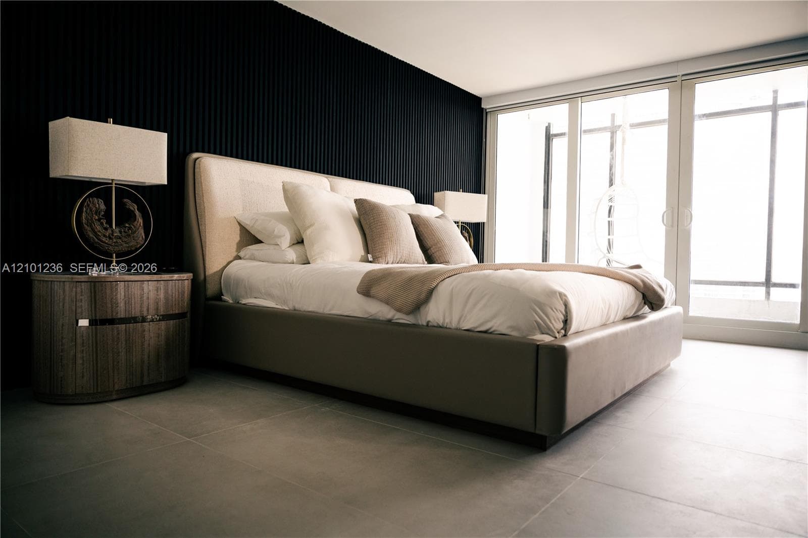 Textured black accent wall, large-format tile flooring, and floor-to-ceiling glass sliding doors