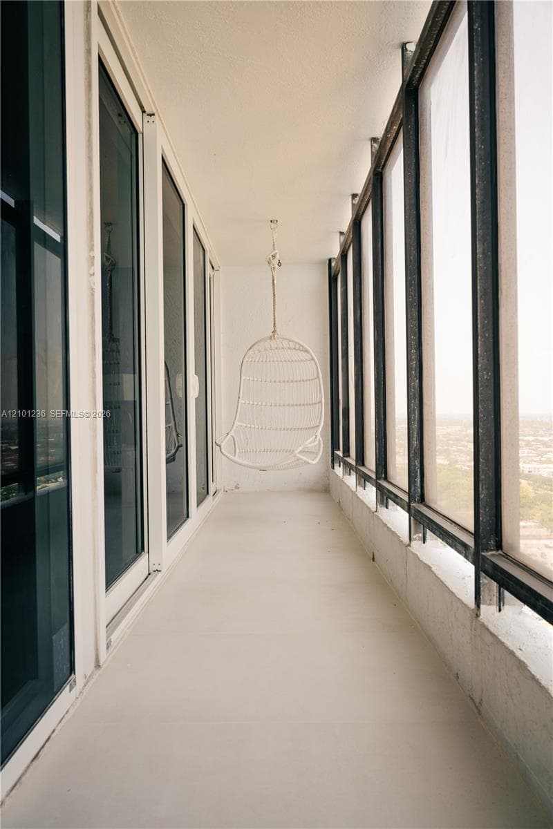 Enclosed balcony featuring floor-to-ceiling windows and metal framing