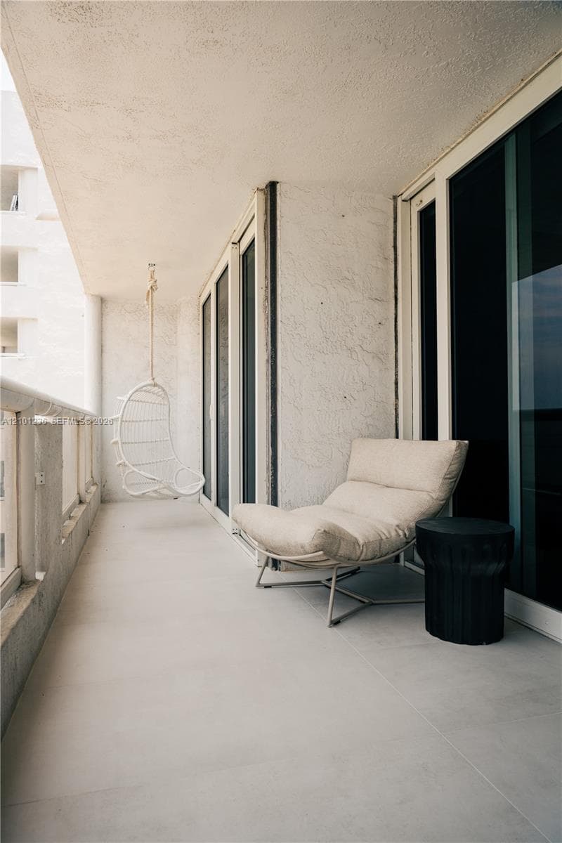 Private balcony featuring large-format tile flooring, textured wall finishes, and floor-to-ceiling sliding glass doors