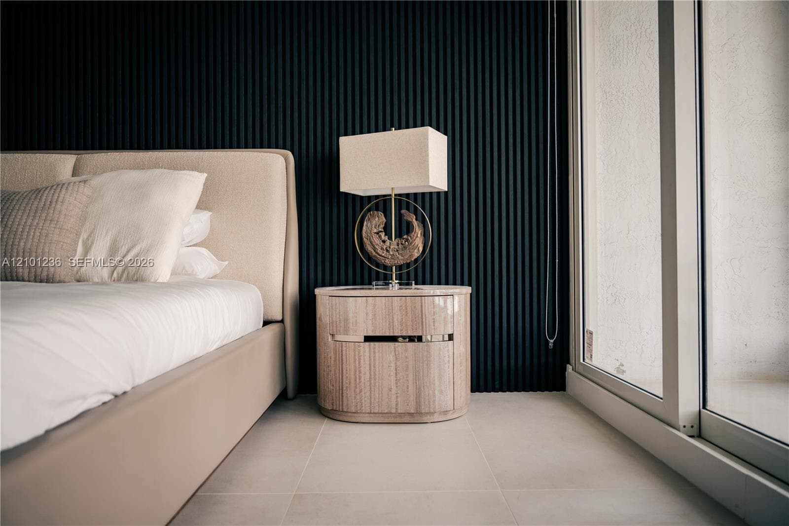 Textured black fluted accent wall, large-format neutral floor tile, and full-height glass sliding door