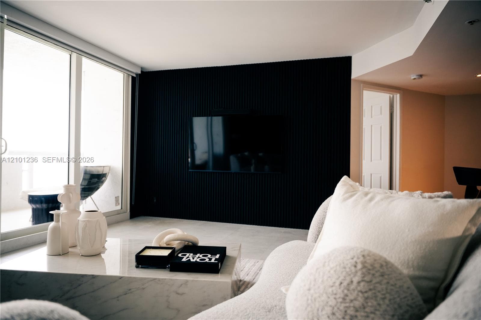 Floor-to-ceiling black vertical slat accent wall, large-format tile flooring, and oversized sliding glass doors