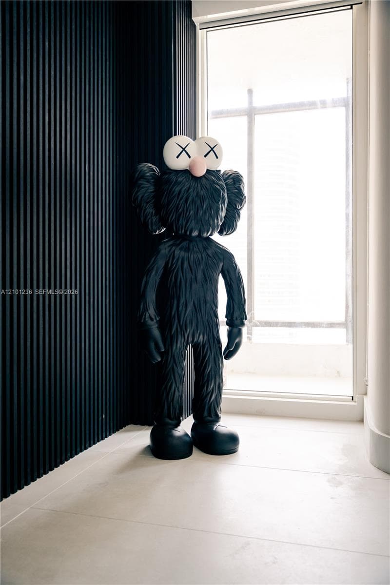 Floor-to-ceiling black vertical slat wall paneling paired with large-format light-toned tile flooring and a full-height window