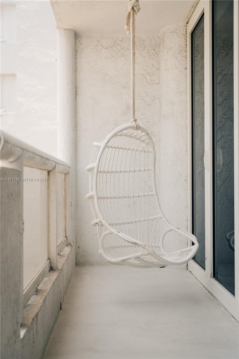 Covered balcony featuring textured stucco walls, smooth concrete flooring, and a low-profile structural railing