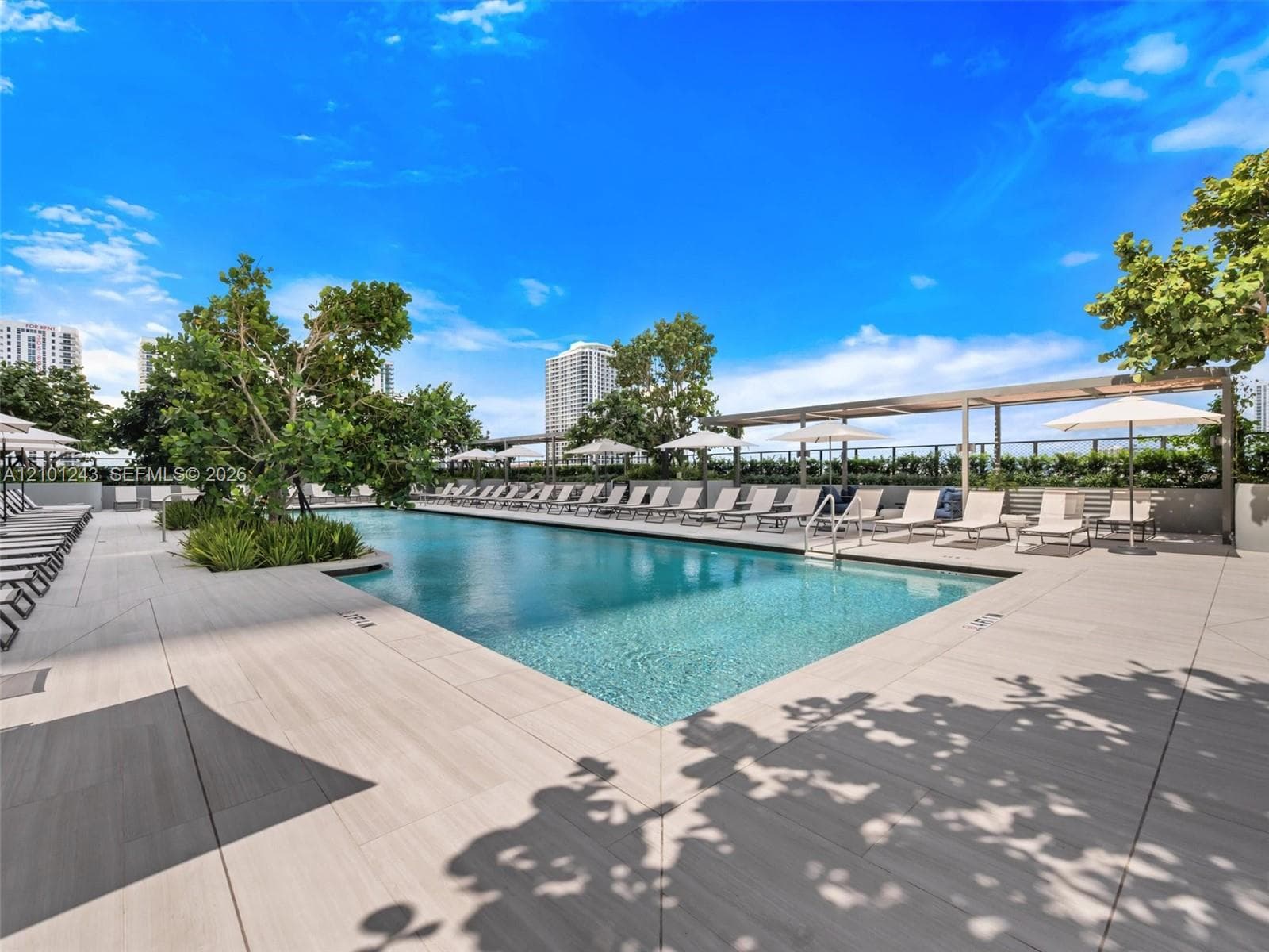 Swimming pool featuring a tiled deck, integrated landscape planters, and a covered pergola area