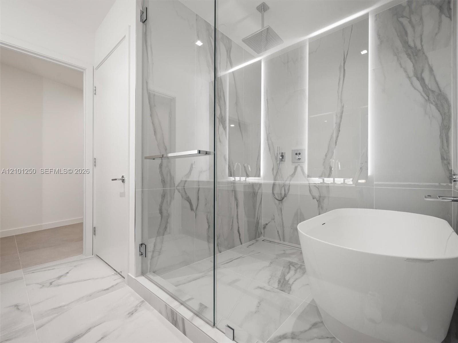 Glass-enclosed shower with large-format veined tile, integrated wall lighting, overhead rain shower head, and freestanding white soaking tub