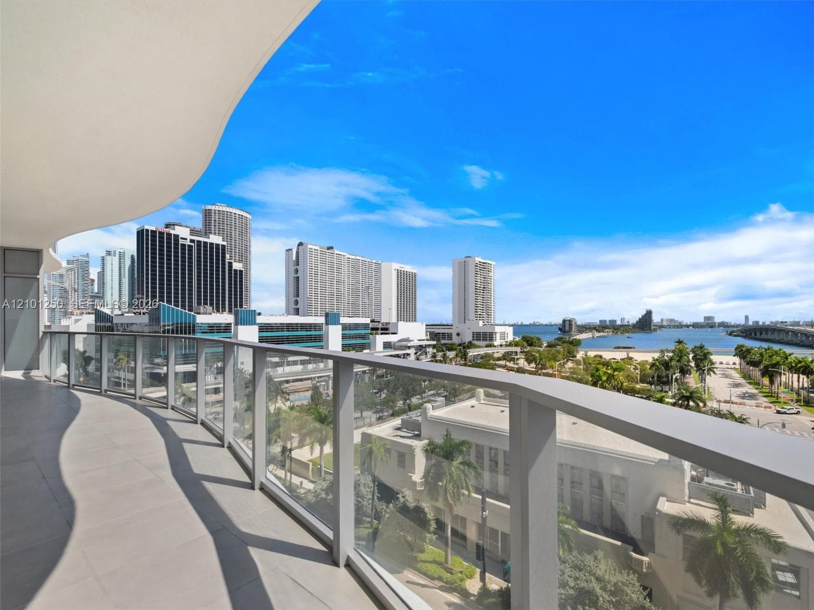 Curved balcony featuring large-format tile flooring and a glass panel railing