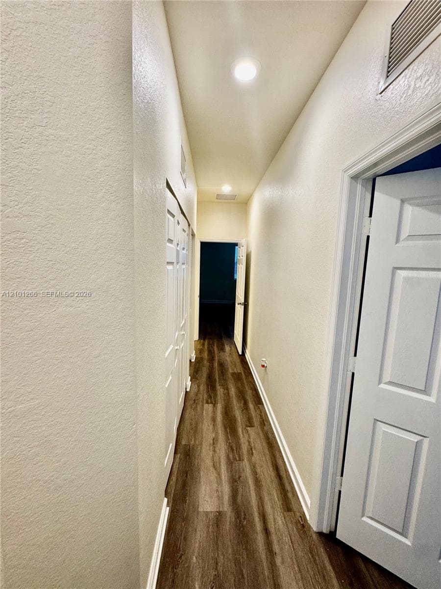 Hallway featuring wood-finish flooring, recessed lighting, and multi-panel interior doors
