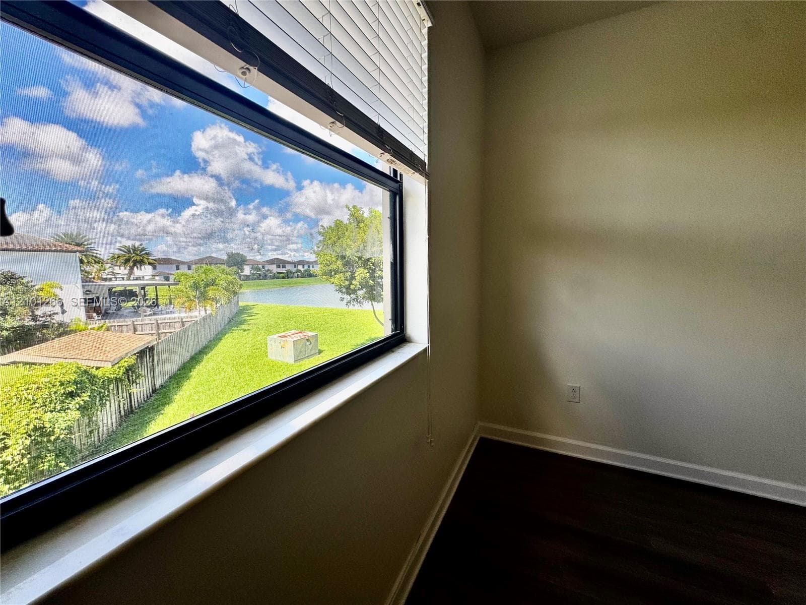 Large window featuring deep sill, wood-finish flooring, and water scenery