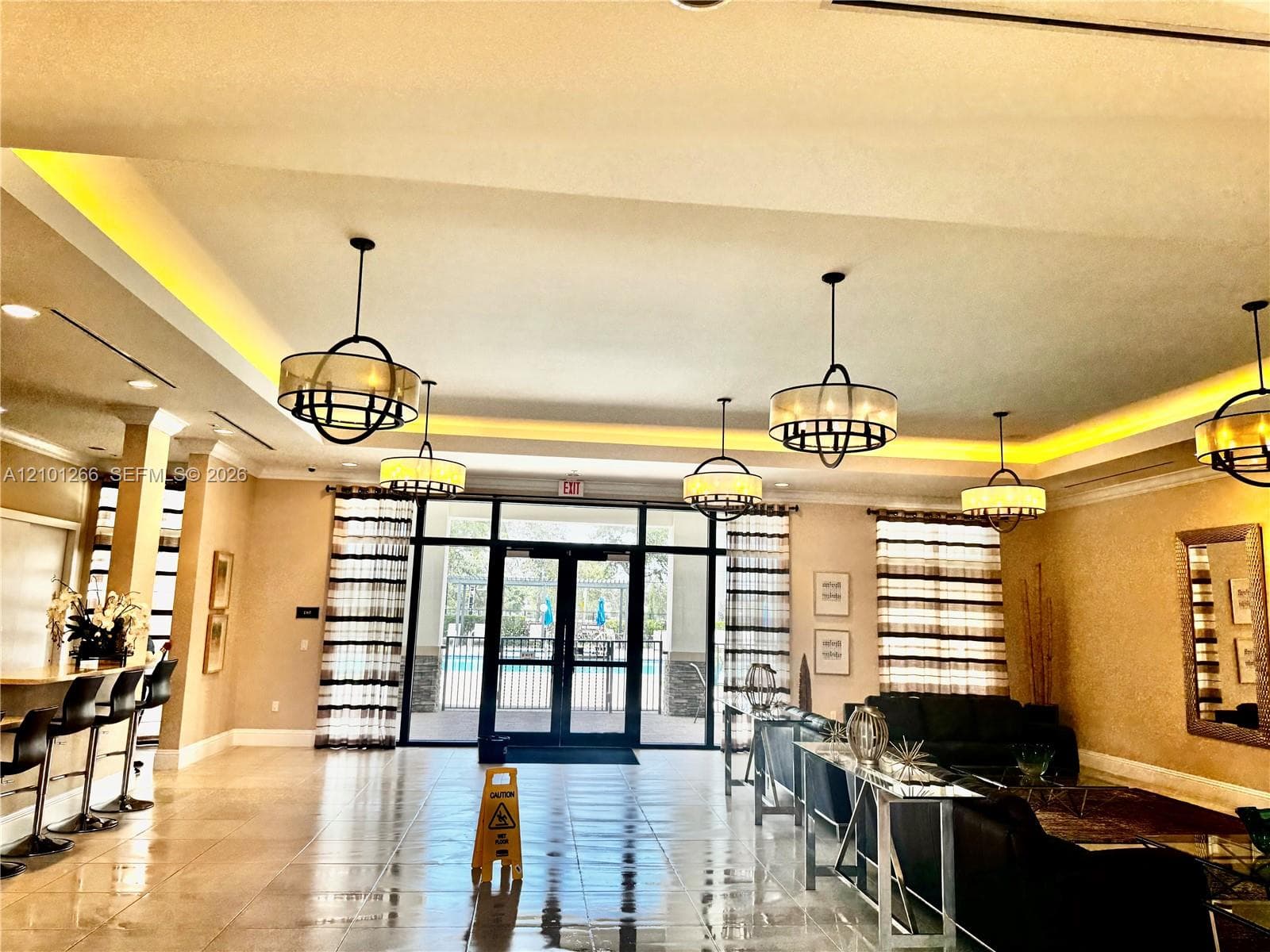 Tray ceiling with recessed ambient lighting, large-format tile flooring, and multiple orb-style pendant chandeliers
