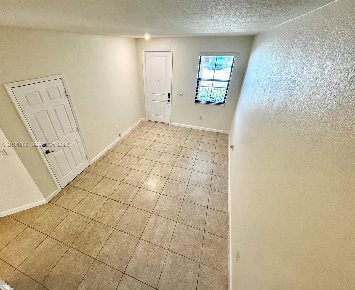 Tile flooring, neutral wall paint, two paneled interior doors, and a single window with integrated blinds