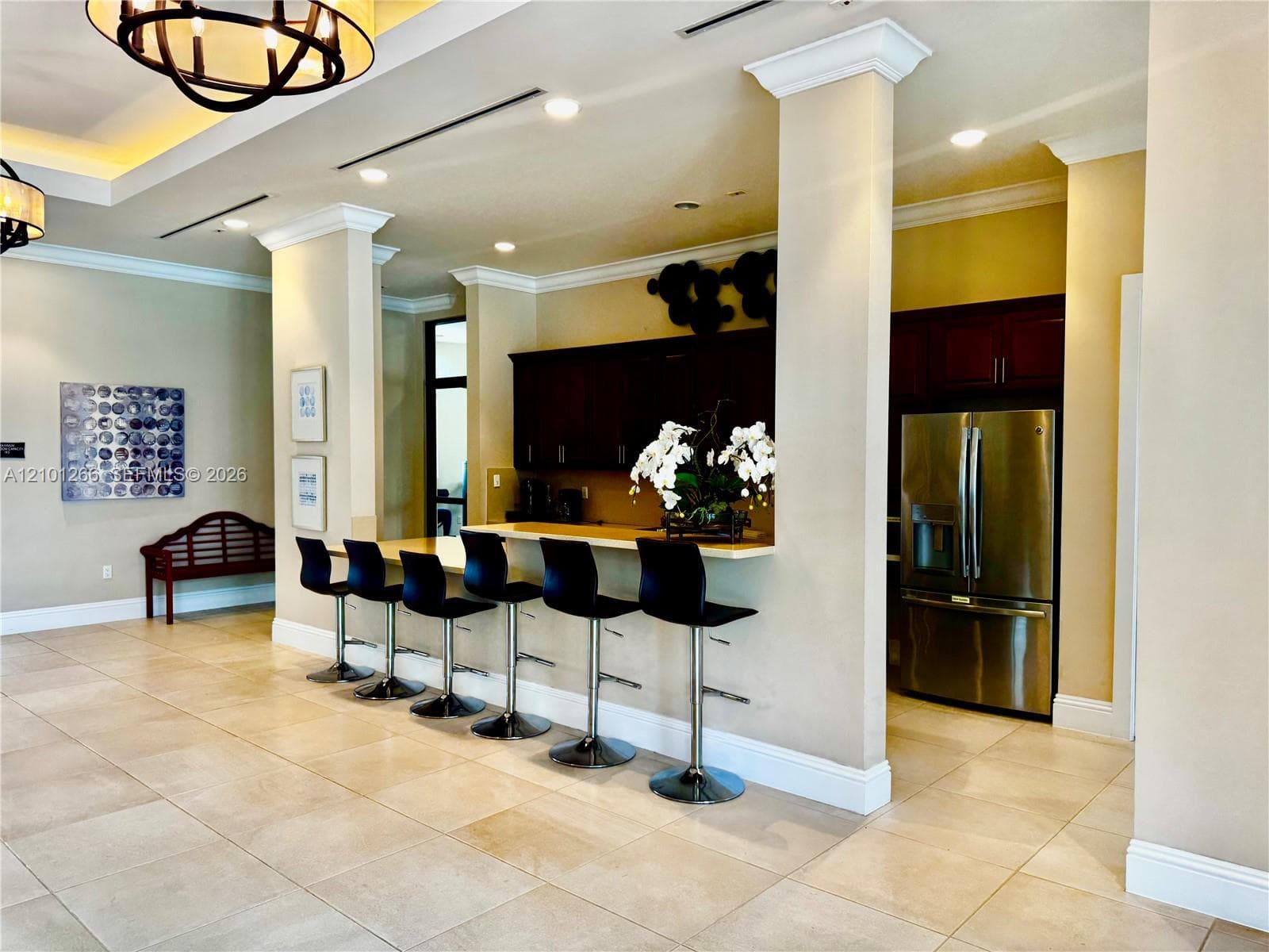 Open kitchen featuring a breakfast bar with stone-finish countertops, dark wood cabinetry, stainless steel refrigerator, tile flooring, and recessed lighting