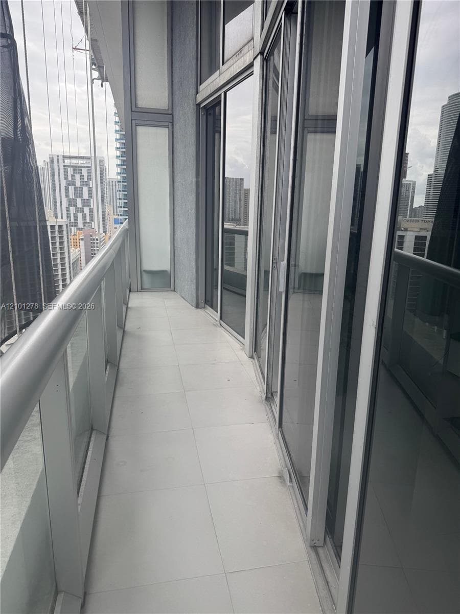 Private balcony featuring expansive floor-to-ceiling glass paneling, tile flooring, and a sleek metal railing