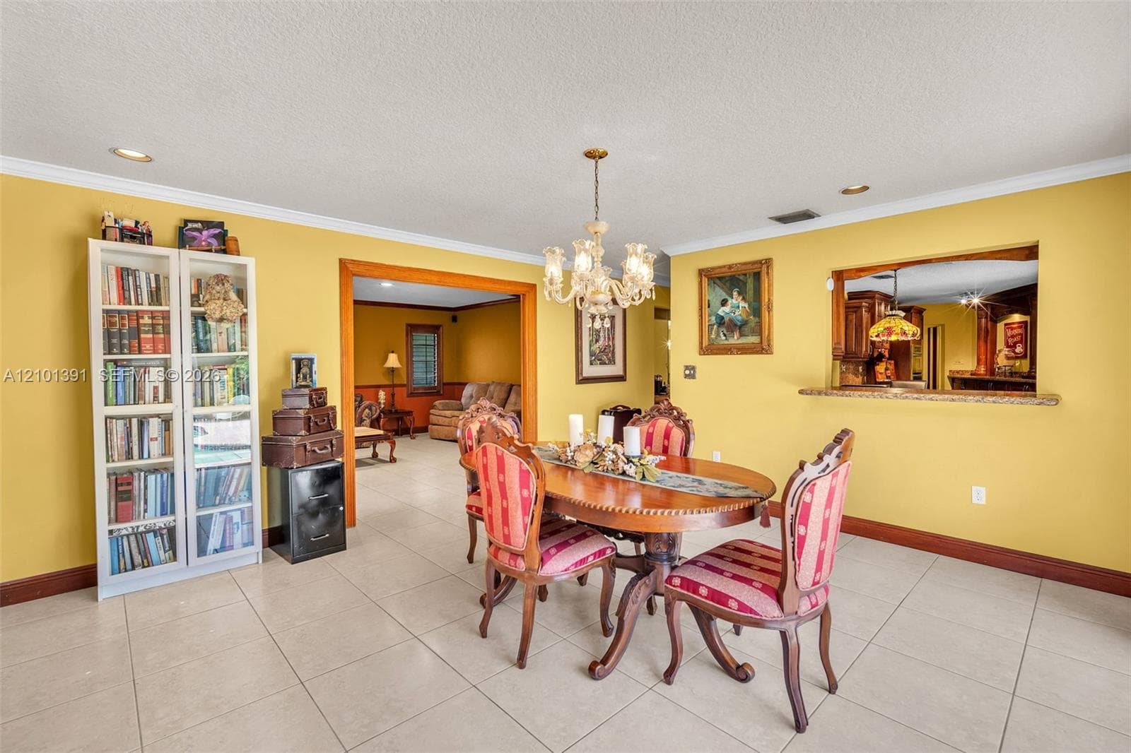 Dining area featuring tile flooring, a decorative chandelier, and a pass-through window with a stone counter