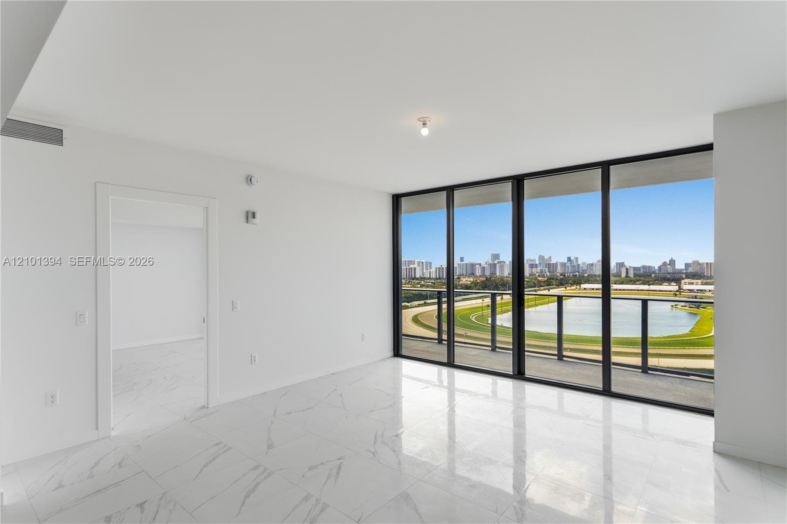 Floor-to-ceiling glass windows, polished tile flooring, black metal-framed balcony railing, and open interior space