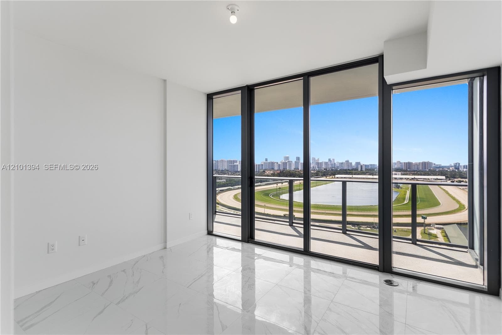 Floor-to-ceiling glass sliding doors, stone-finish tile flooring, and an expansive balcony featuring a metal railing and panoramic exterior scenery