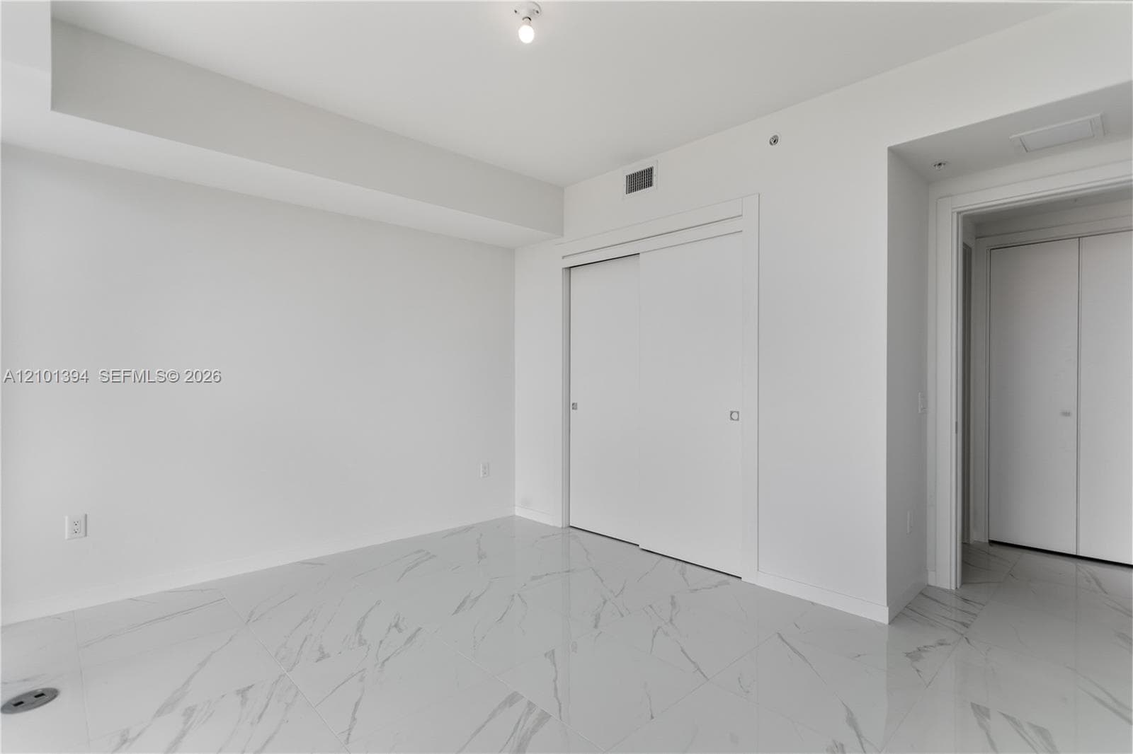 Interior space featuring large-format tile flooring with a neutral veined pattern, floor-to-ceiling sliding closet doors, and recessed ceiling lighting