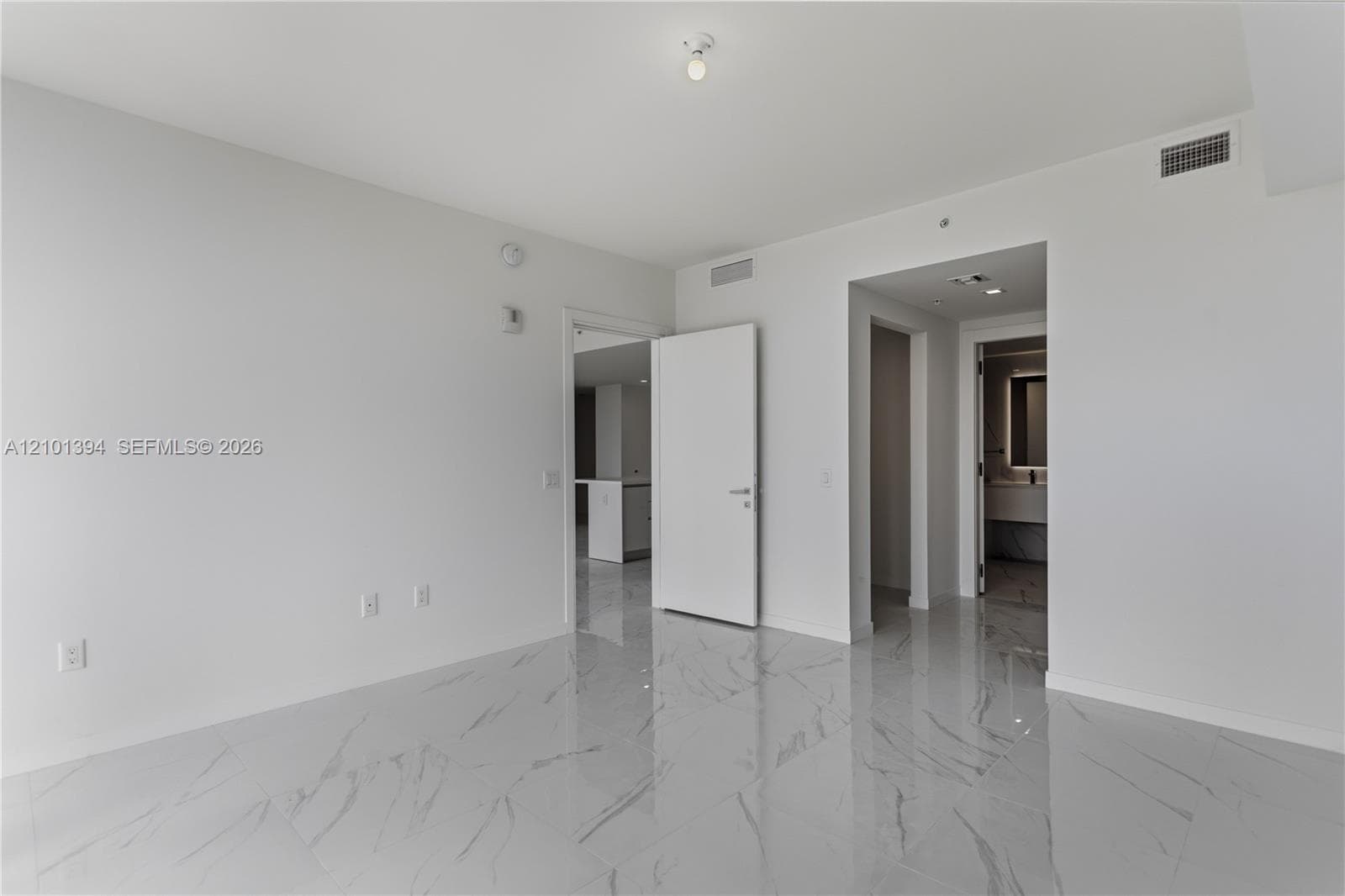 Open interior space featuring polished stone-finish floor tiling with veining and smooth white wall surfaces