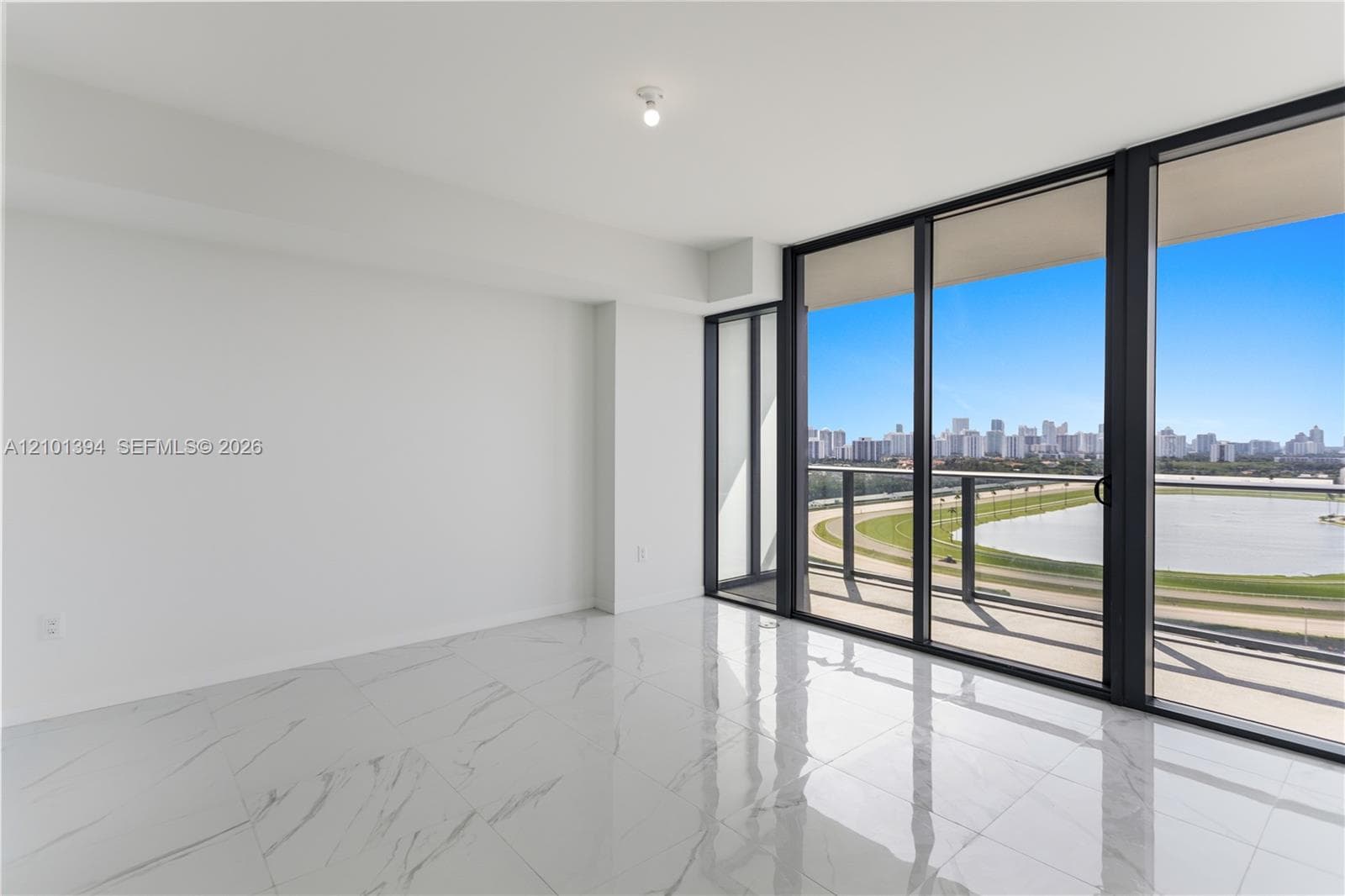 Floor-to-ceiling glass sliding doors, stone-finish tile flooring, and a private balcony with metallic railing