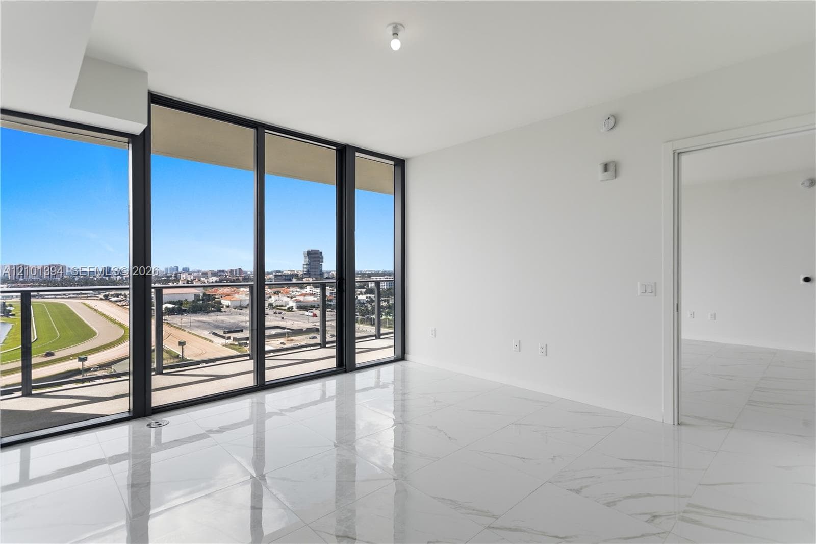 Floor-to-ceiling windows, polished tile flooring, and a glass-paneled balcony featuring an expansive exterior outlook