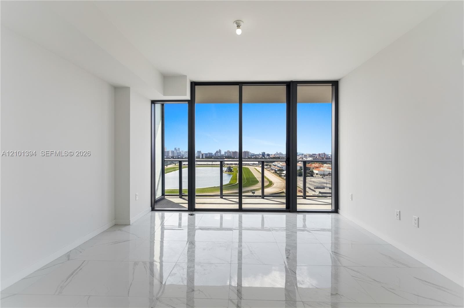 Floor-to-ceiling sliding glass doors, large-format stone-finish tile flooring, and integrated balcony with metal railing