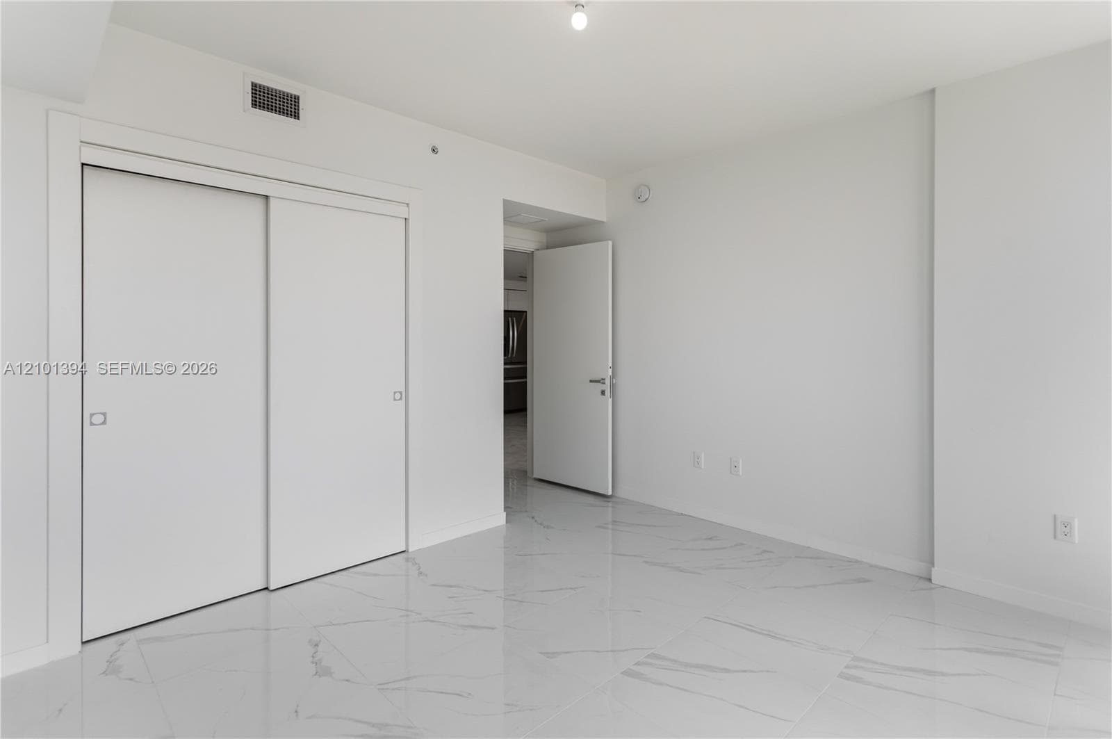 Large-format stone-style tile flooring with neutral veining, sliding-door closet system, and white interior doors with contemporary hardware