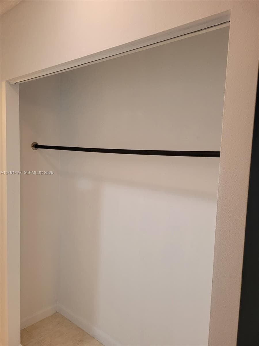 Storage space featuring smooth wall finishes and a black metal closet rod