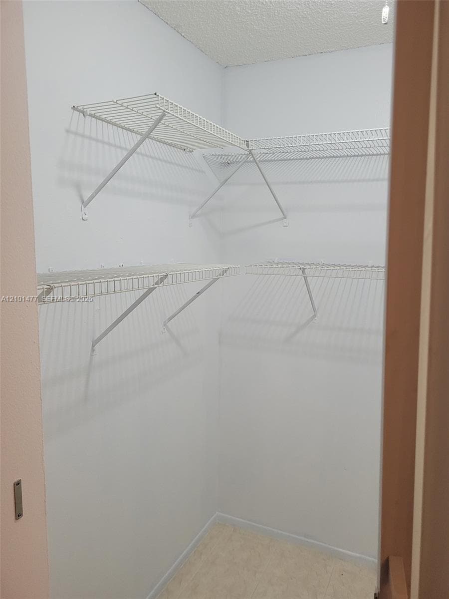 Storage area featuring dual-level white wire shelving and light-toned flooring