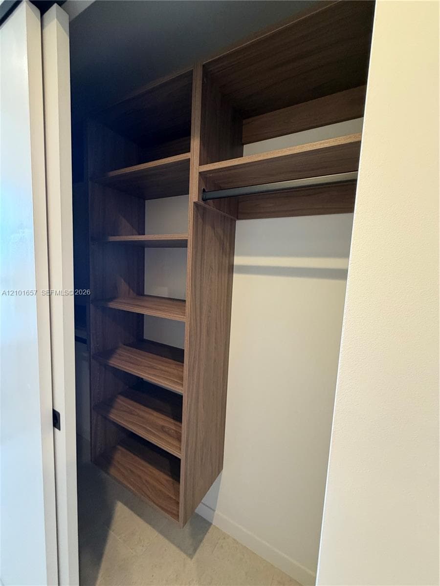 Custom built-in storage unit featuring wood-finish shelving, an integrated hanging rod, and a space-saving sliding door