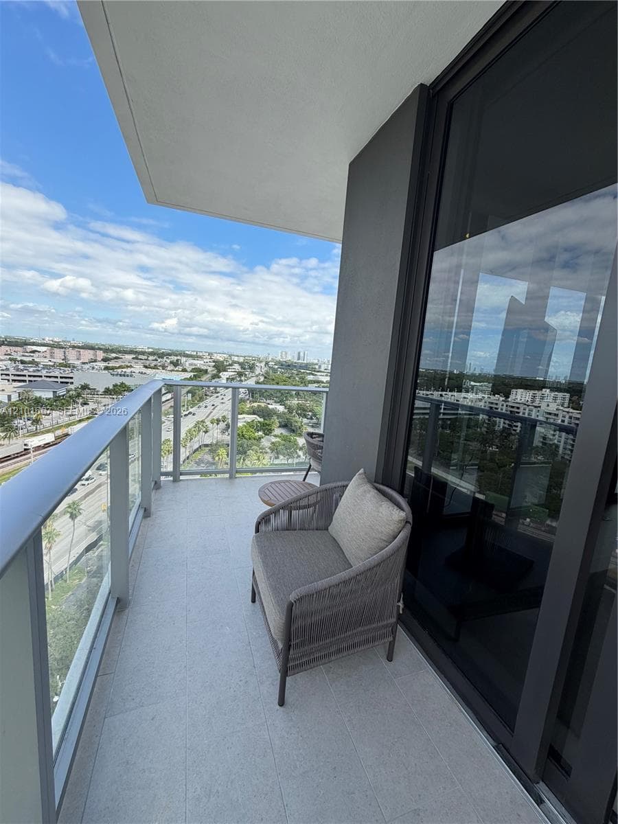 Covered balcony featuring concrete flooring, a glass panel railing, and expansive sliding glass doors