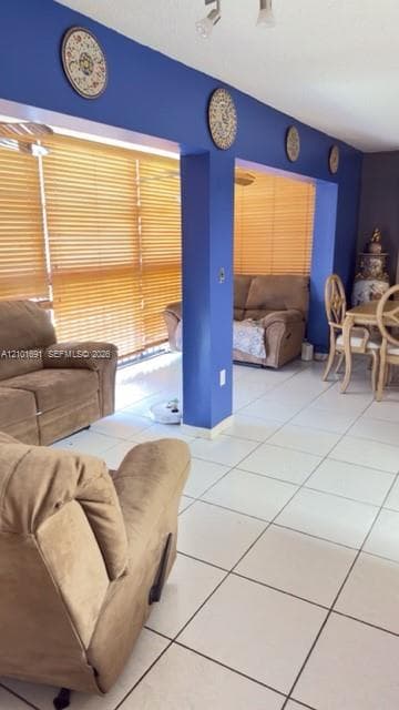 Large-format tile flooring, oversized horizontal window blinds, and recessed track lighting